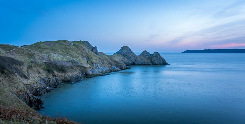 A sunset view of 3 Cliffs Bay which is a family friendly walk in the Gower
